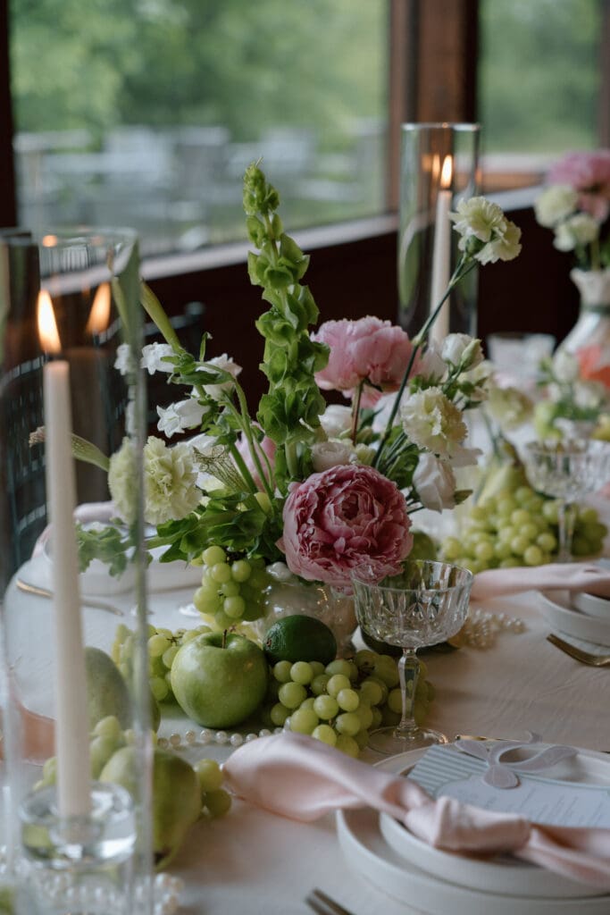 Cottage core wedding tablescape with florals, apple, grapes, and candles at Rivers Edge Resort Manitoba wedding venue