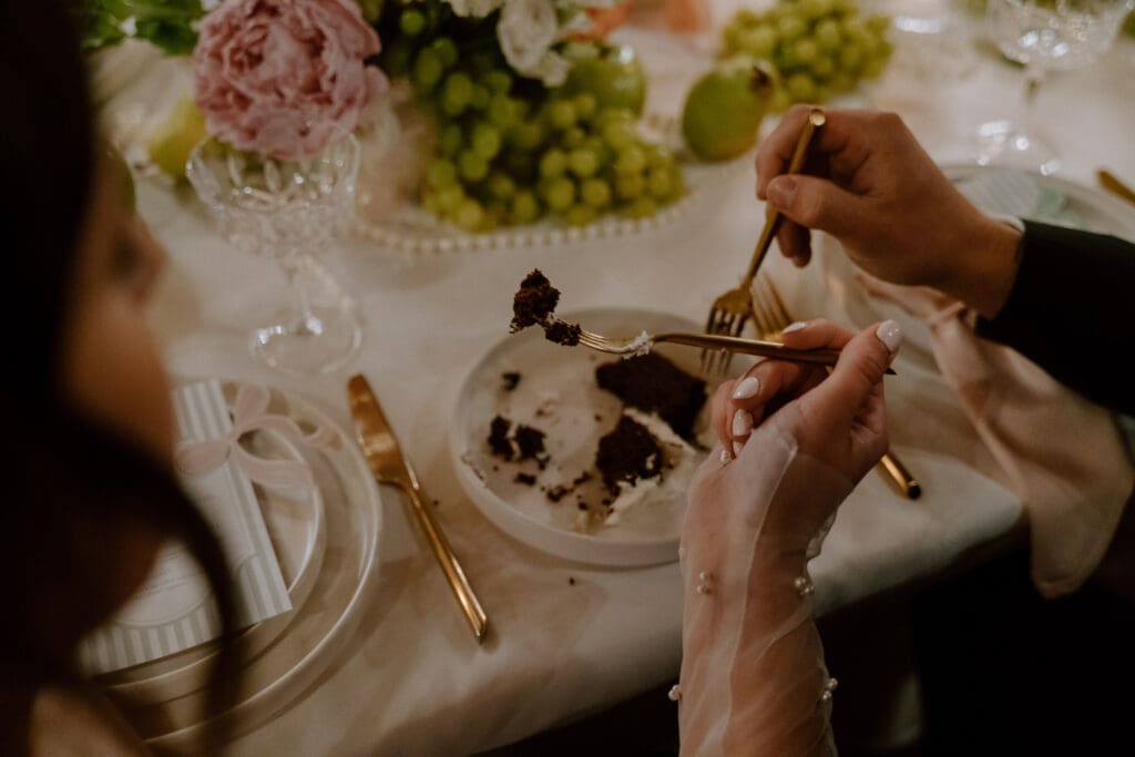 Candid moment of couple eating cake together during romantic cottage core wedding reception at Rivers Edge Resort Manitoba