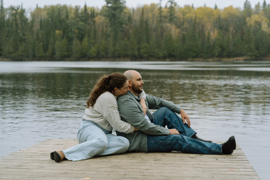 A couple hugging on the dock during an engagement session at Hunt Lake, Manitoba