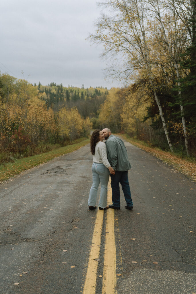 A couple kissing on the road with autumn leaves in the background