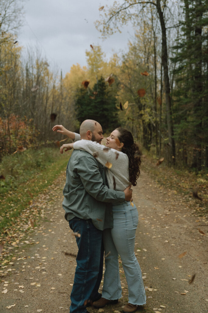 A couple kissing in the leaves during an engagement session on the hunt lake trail in Manitoba
