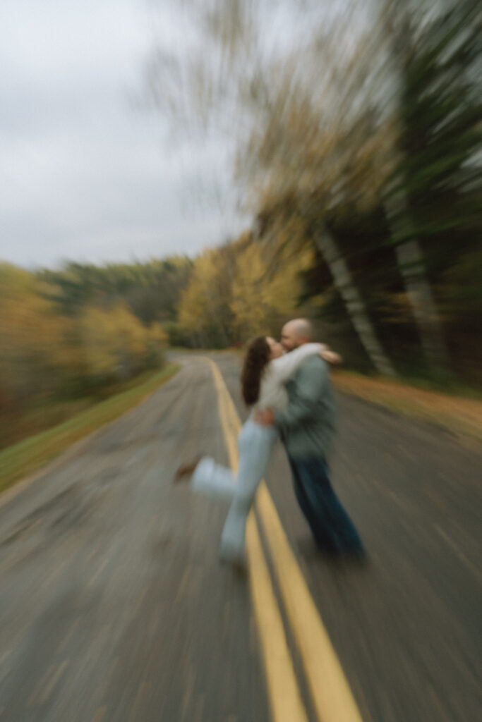 A couple kissing on the road with autumn leaves in the background