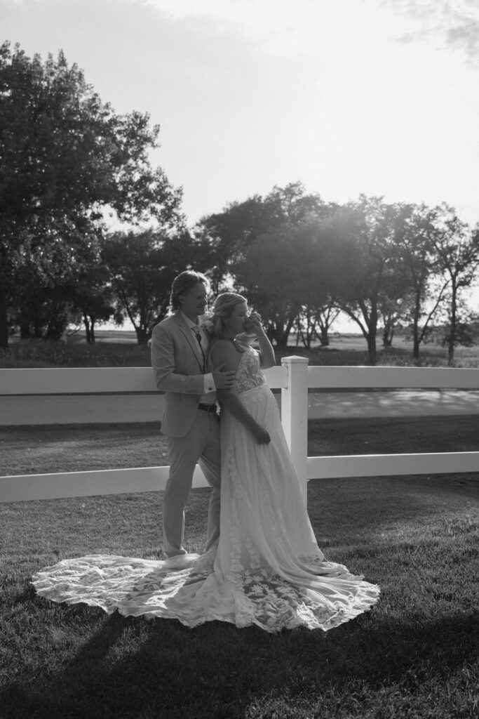 Bride and groom leaning on fence in editorial style wedding photos