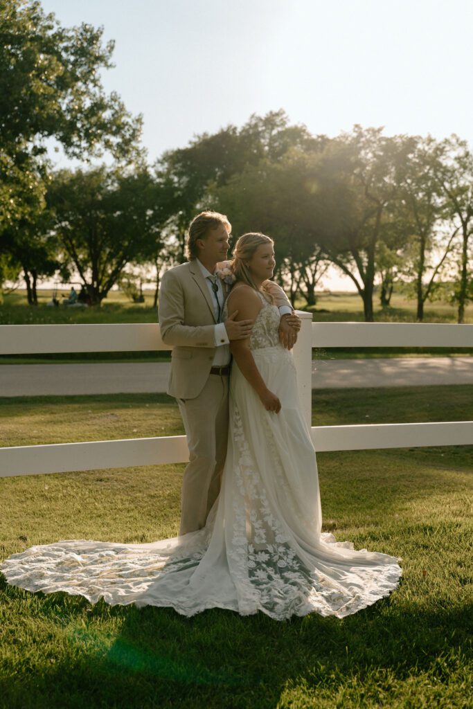 Bride and groom leaning on fence in editorial style wedding photo