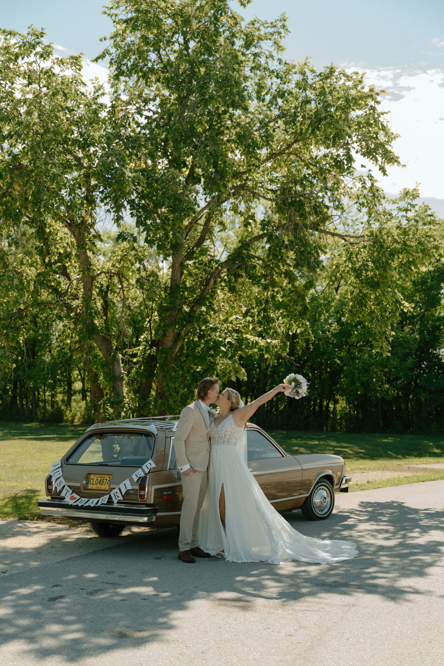 Wedding photo of bride and groom with old school car