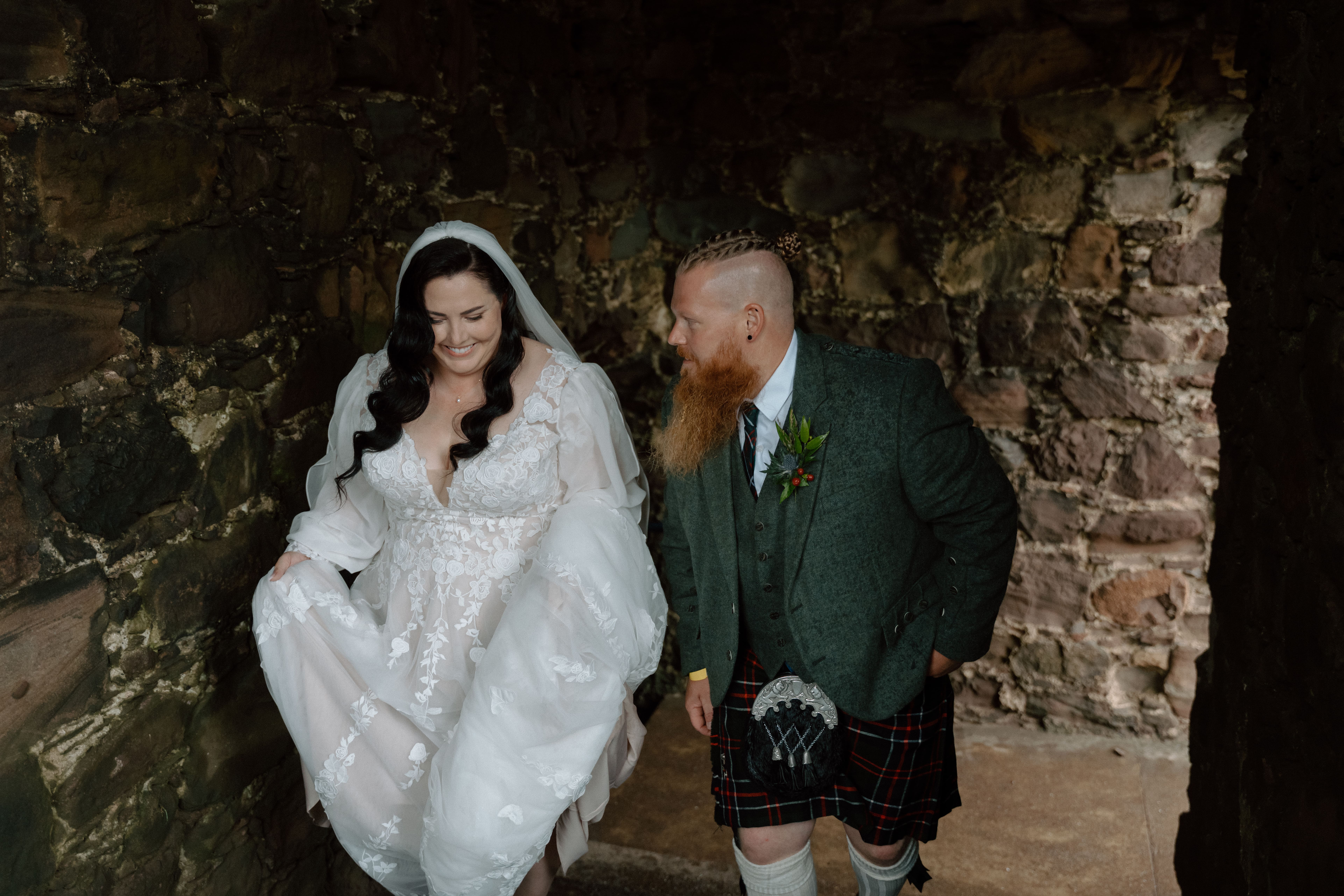 wedding couple walking up the staircase of castle wedding ceremony setup within historic stone walls at Dunnottar Castle