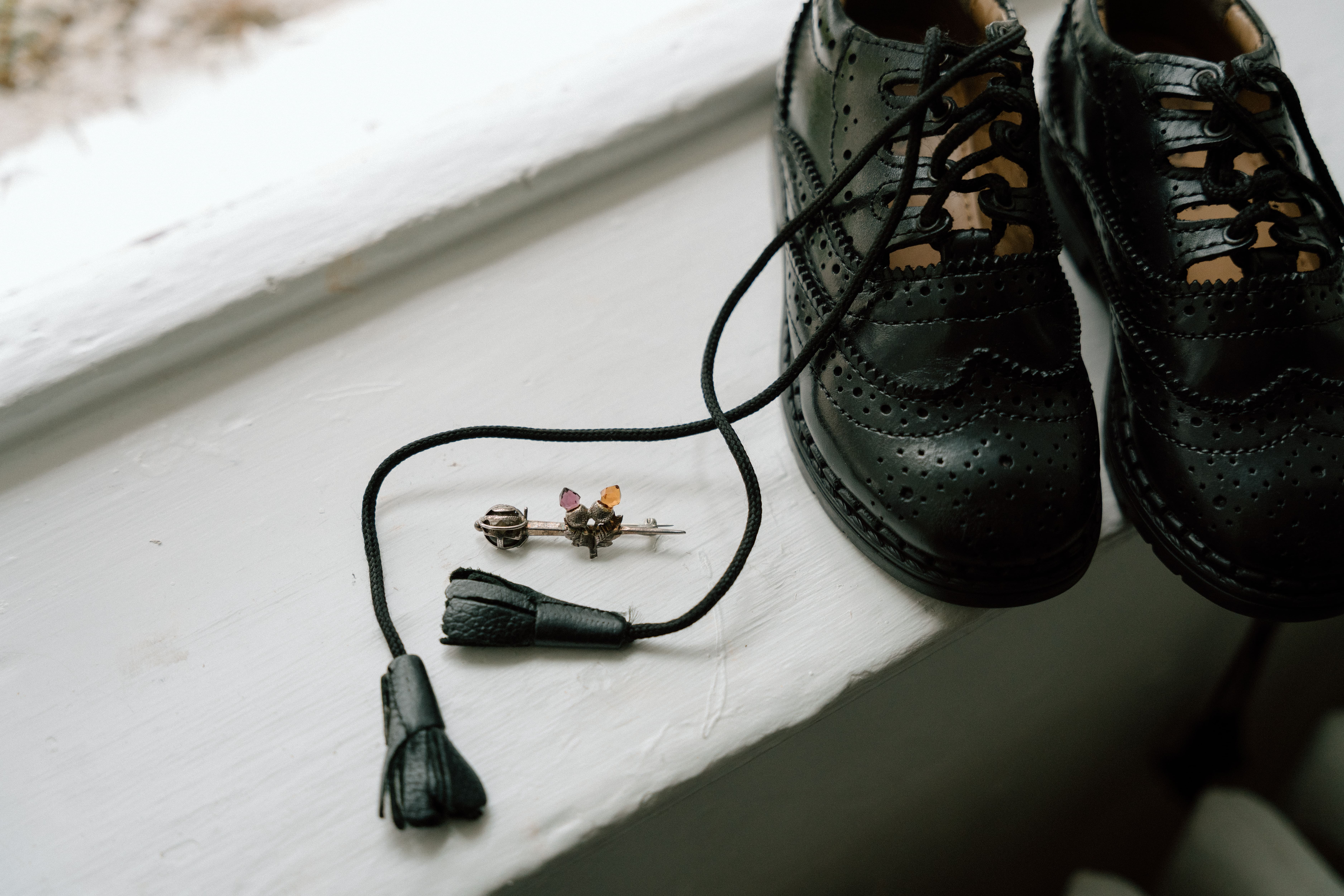 Natural wedding detail photography featuring the groom's pins, shoes, and personal items during bridal preparations at Elsick House.
