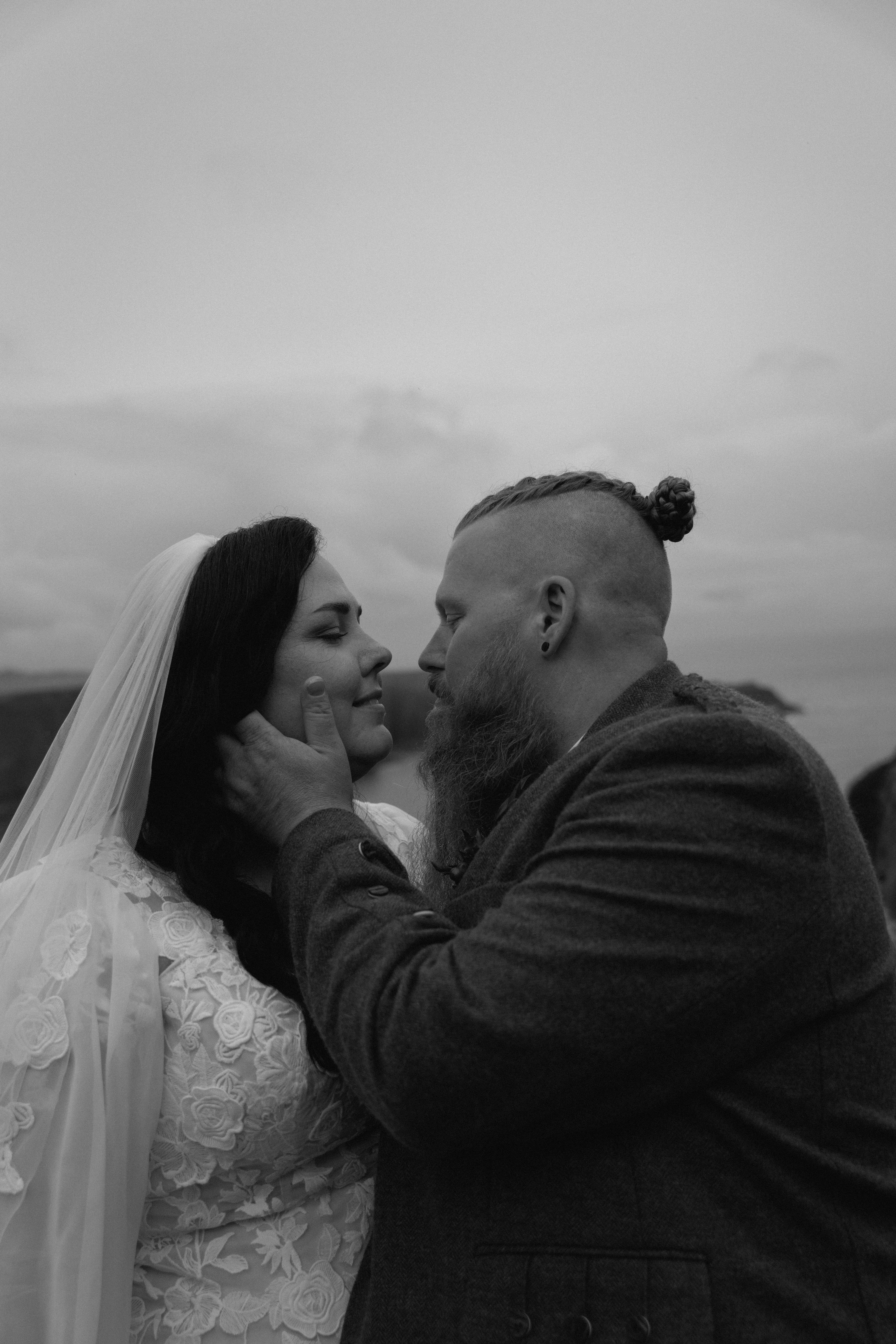Close-up of an artistic documentary wedding image of a couple almost kissing in Stonehaven with stormy skies in the background.