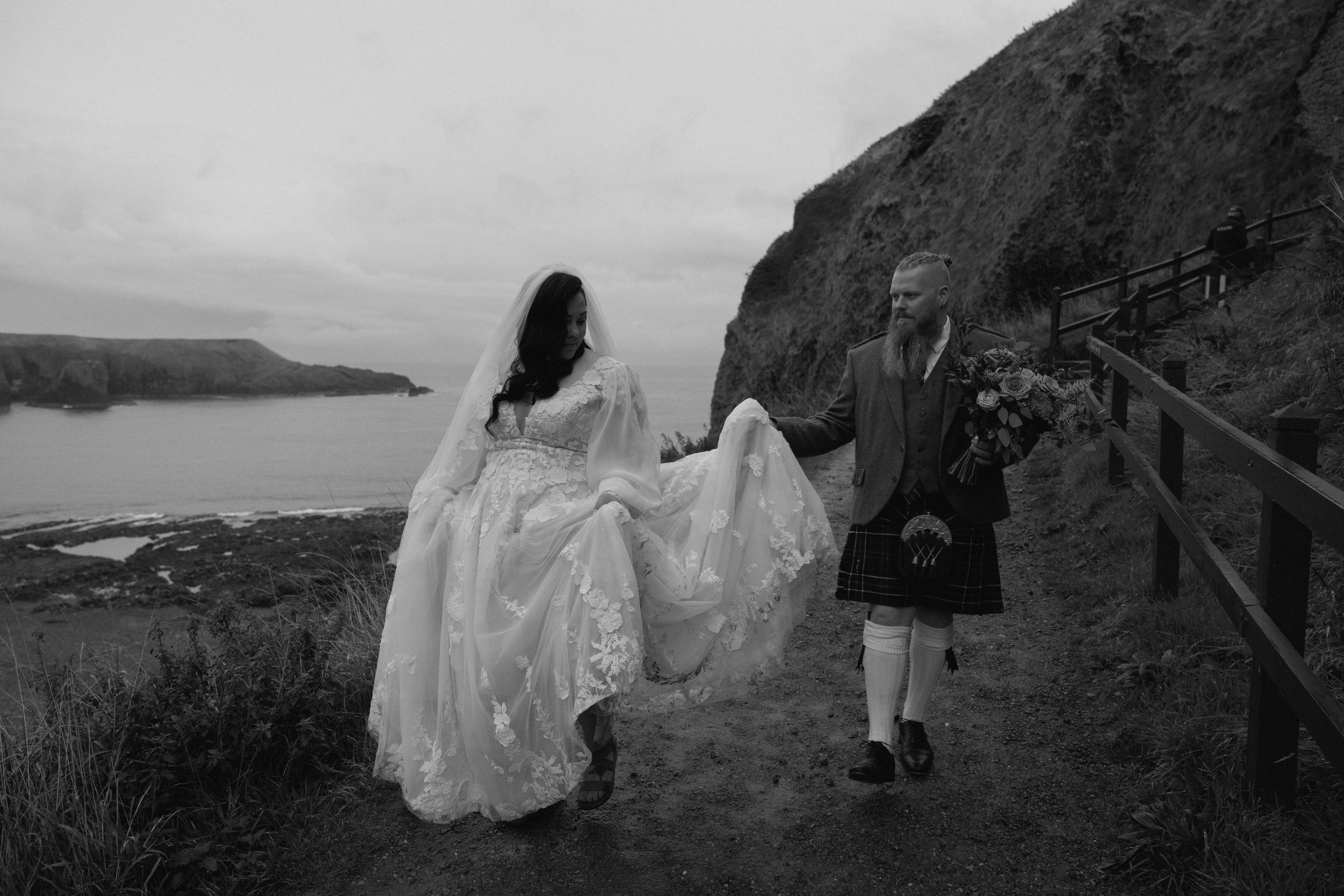 Candid wedding portraits of a couple walking down Scottish coastline near Stonehaven, captured in a relaxed, unposed documentary style.