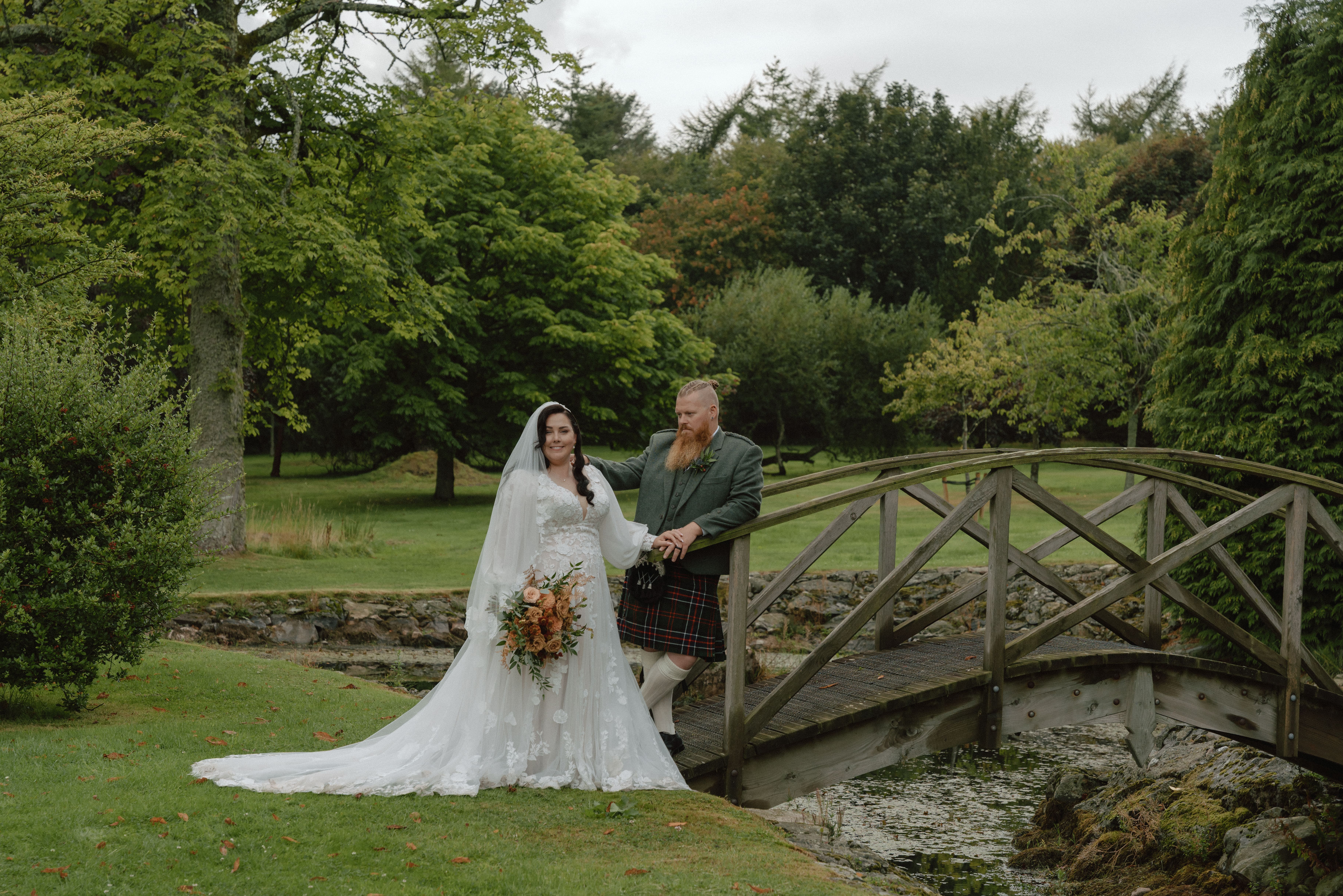 Intimate documentary wedding photo near Dunnottar Castle featuring a couple in a natural green landscape with trees and shrubs as the groom and bride pose for their wedding portrait.