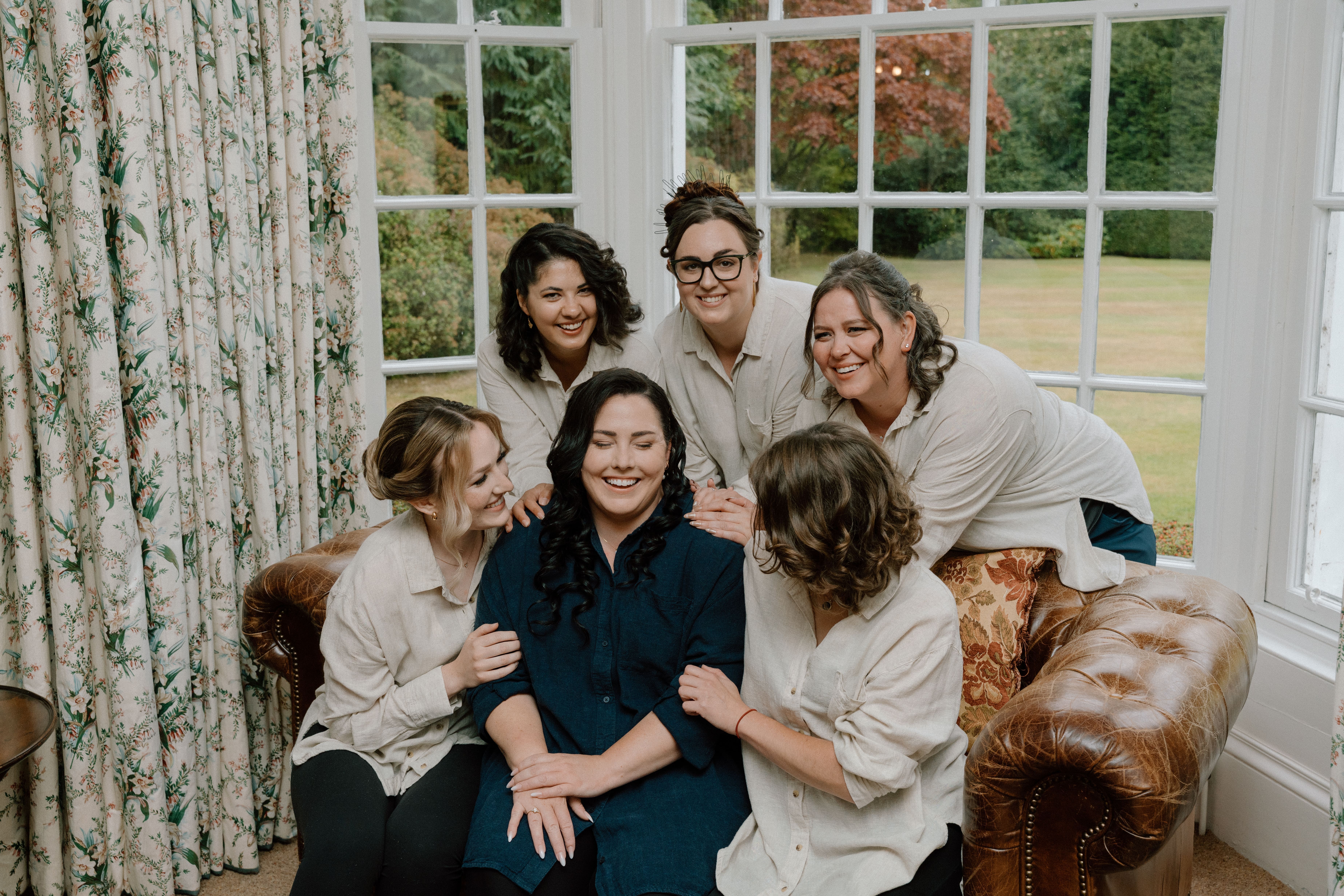 Candid bridal preparation moment featuring the bride laughing with her bridesmaids in soft natural light at Elsick House near Stonehaven.