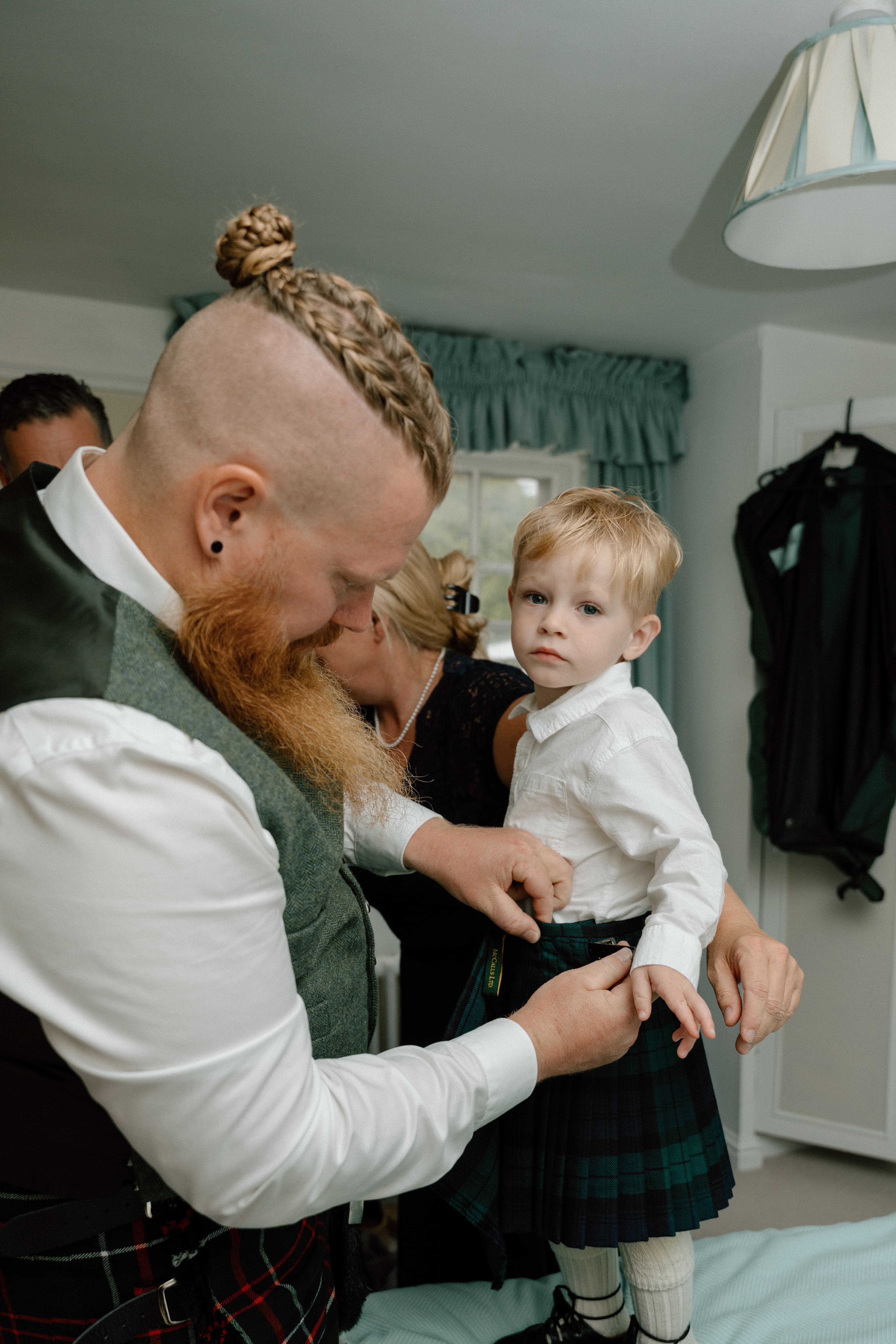 Documentary wedding photography of the groom helping his son get dressed during relaxed wedding preparations at Elsick House near Stonehaven.