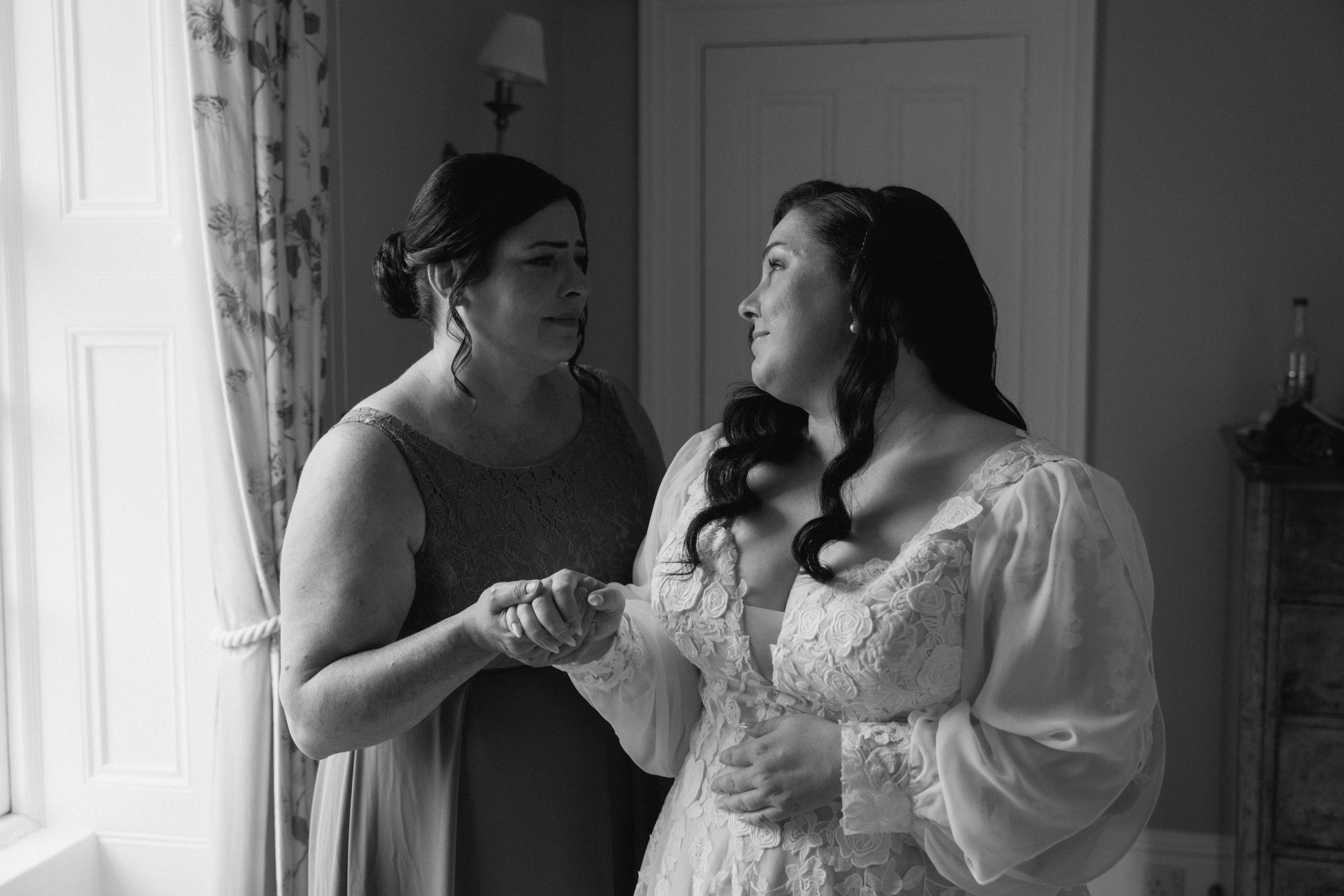 Intimate documentary wedding image of the bride and her mother sharing a heartfelt smile during getting ready moments in Stonehaven, Scotland.