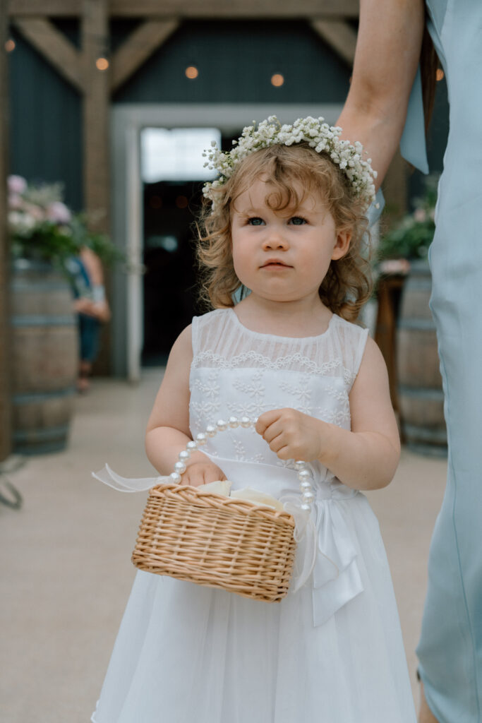 Baby flower girl getting ready to walk down the aisle at a wedding at Hawthorne Estates in Manitoba