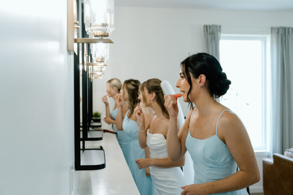 Julianna and her bridesmaids getting ready together in matching mirrors during a candid Manitoba wedding morning