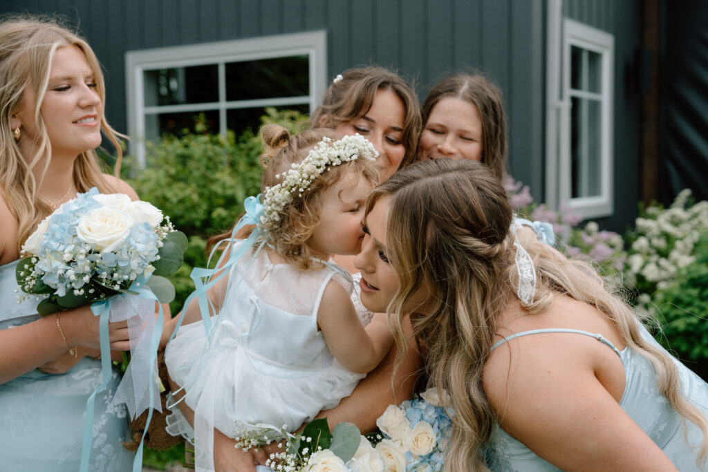 Flower girl surrounded by bridesmaids during an outdoor wedding celebration