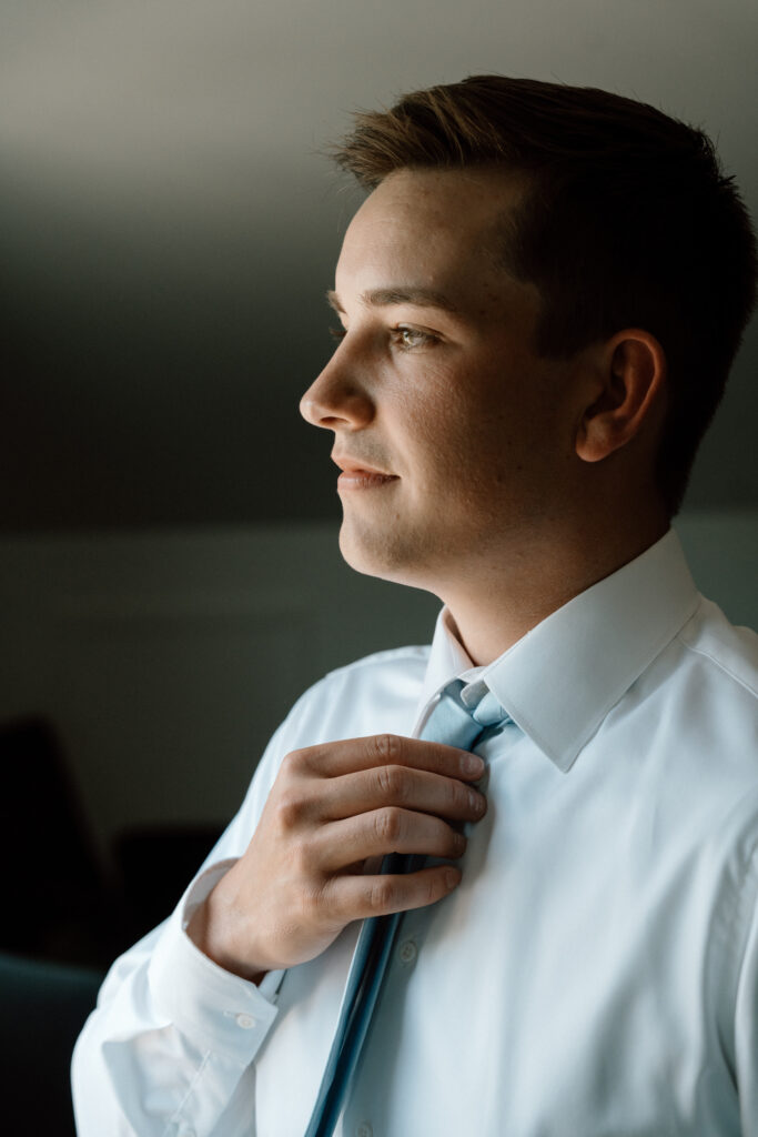 Groom adjusting his tie before the wedding at The White Poplar, captured in a natural wedding getting ready moment