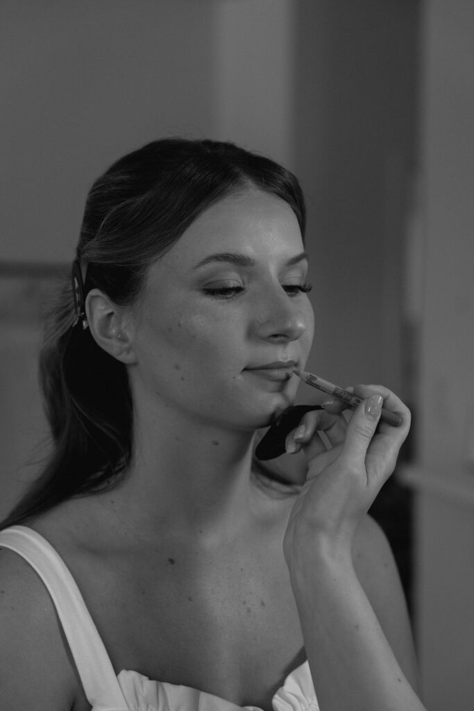 Black and white close-up of Julianna having her lipstick applied during her elegant wedding getting ready photos
