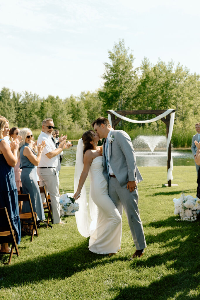 Julianna and Cole sharing a dip kiss while their wedding guests celebrate at The White Poplar