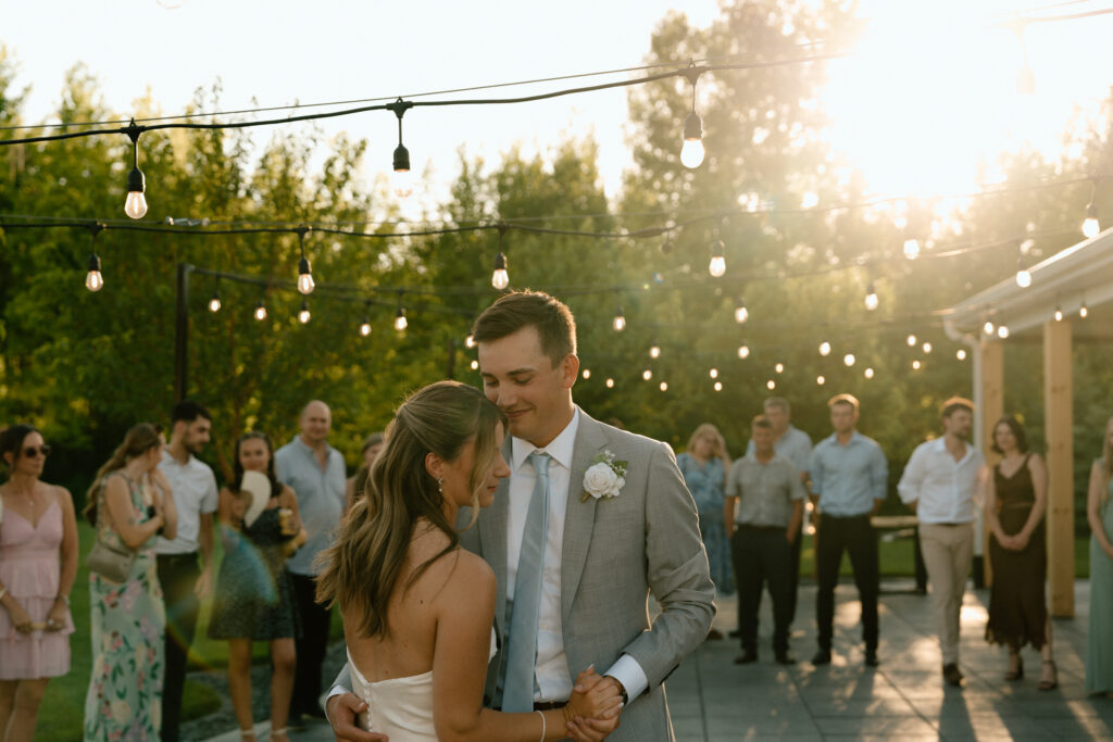 Julianna and Cole sharing their first dance at The White Poplar during golden hour with twinkle lights