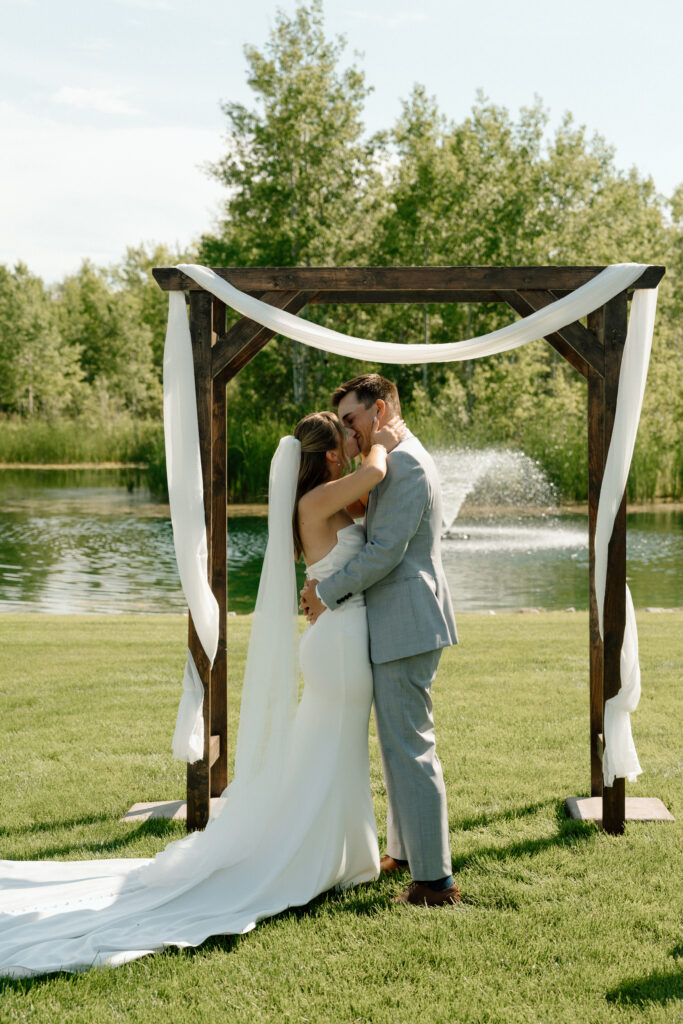 Bride and groom sharing their first kiss as newlyweds during their wedding ceremony at The White Poplar