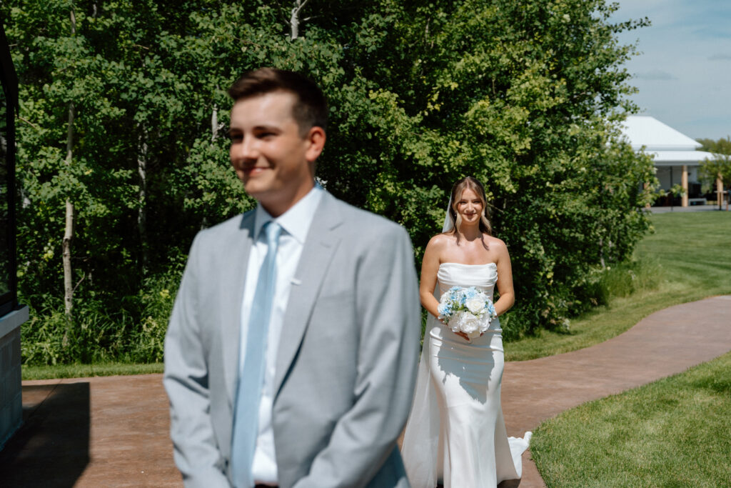 Cole waiting while Julianna walks toward him during a classic first look moment at The White Poplar in Manitoba