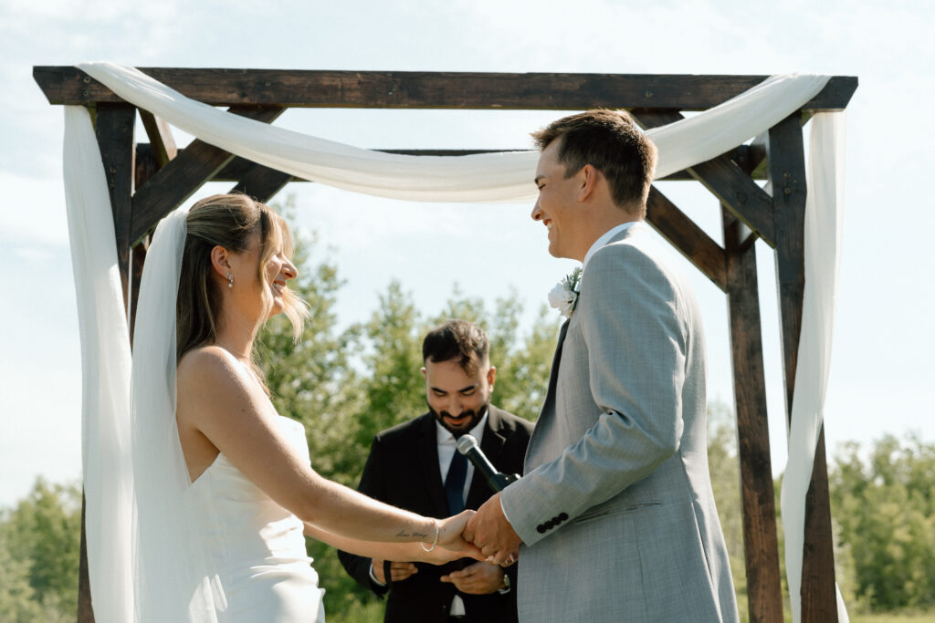 Julianna and Cole laughing with their officiant during their outdoor, nature wedding ceremony at The White Poplar