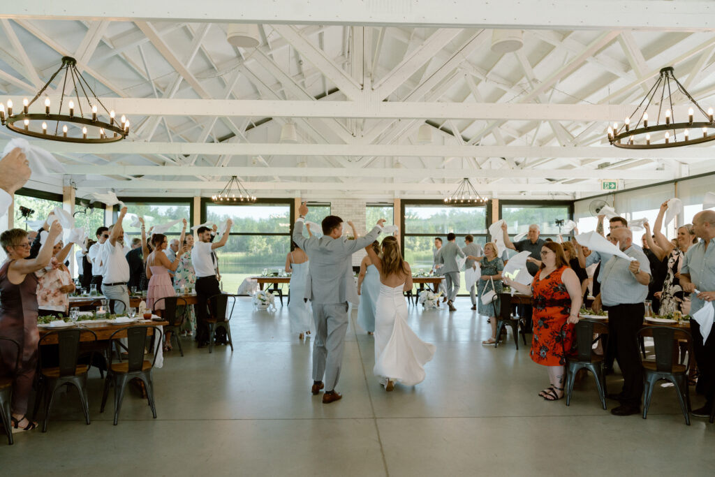 Julianna and Cole's wedding party and guests celebrating their reception entrance at The White Poplar in Manitoba
