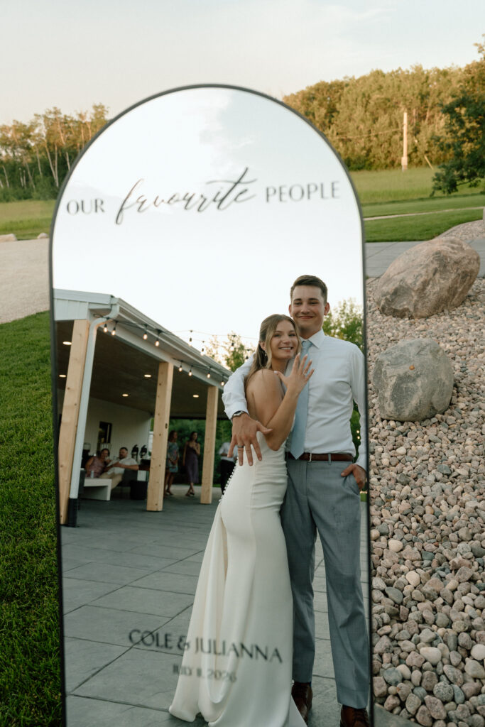 Julianna and Cole showing their wedding rings in the reflection of a full-length mirror at The White Poplar