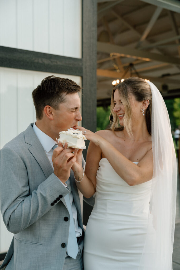 Julianna and Cole laughing together during a fun candid wedding cake photo at The White Poplar in Manitoba