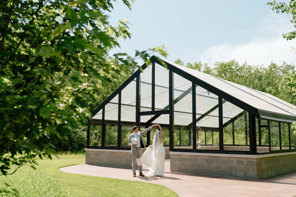 Bride and groom dancing in front of a glass building at The White Poplar in Manitoba