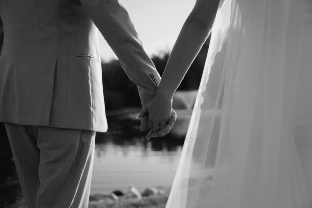Julianna and Cole holding hands in a clean, classic black and white wedding portrait at The White Poplar