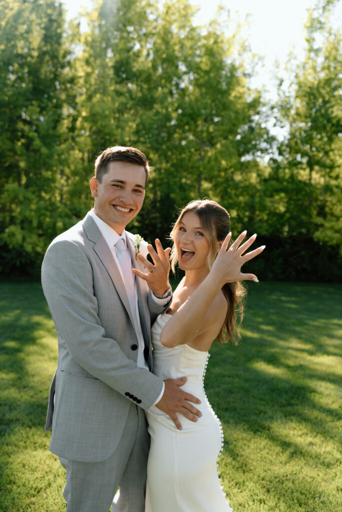 Julianna and Cole laughing and showing their wedding rings in a natural editorial wedding portrait at The White Poplar