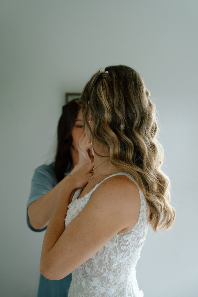 Kayla adjusting her wedding gown while getting ready for her Hawthorne Estates wedding in Manitoba