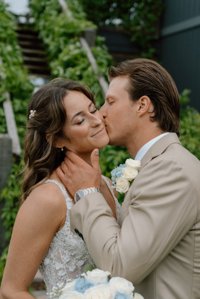 Close-up portrait of Myles kissing Kayla on the cheek at their Hawthorne Estates wedding