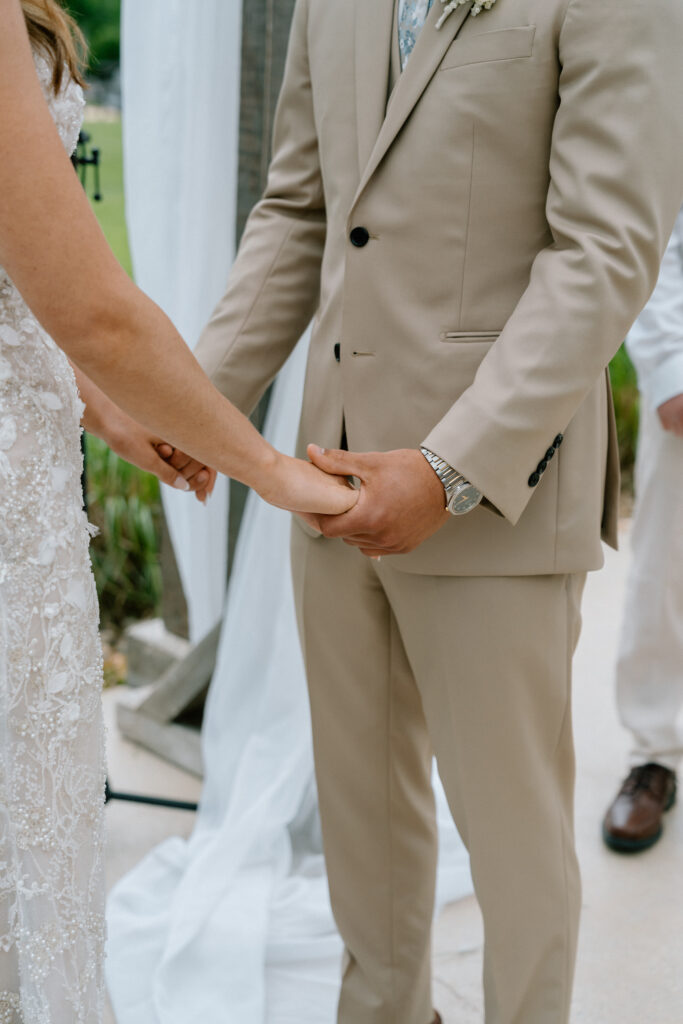 Close-up of Kayla and Myles holding hands during their wedding ceremony at Hawthorne Estates in Manitoba