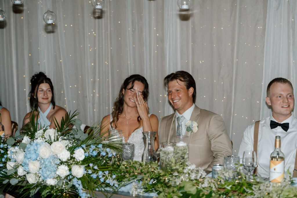 Kayla and Myles sitting together during their wedding reception at Hawthorne Estates