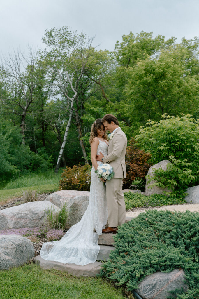 Kayla and Myles standing together on a rock surrounded by trees at Hawthorne Estates in Manitoba