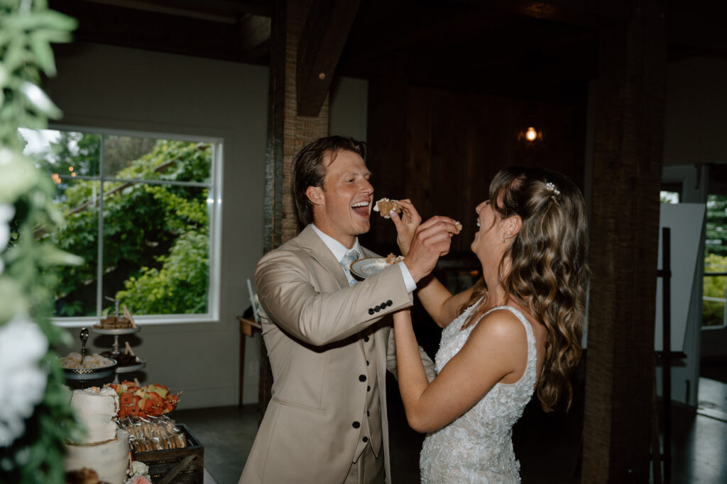 Kayla and Myles feeding each other wedding cake during their reception at Hawthorne Estates in Manitoba