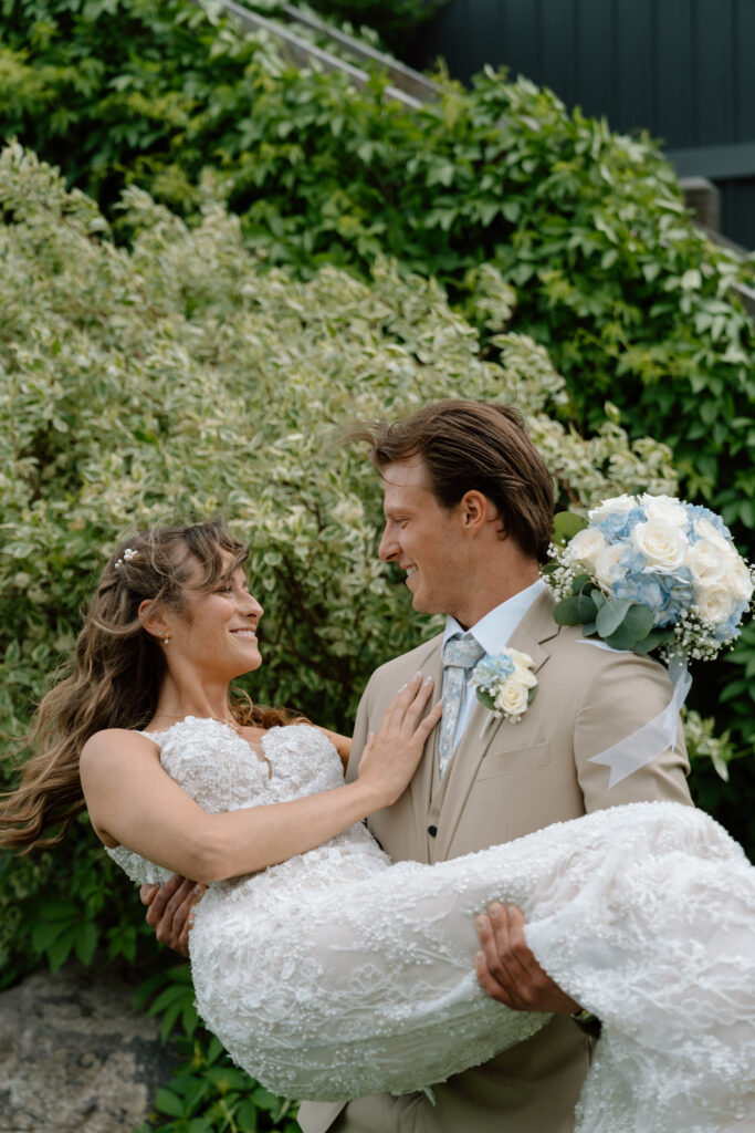 Myles carrying Kayla in his arms during their wedding portraits at Hawthorne Estates in Manitoba