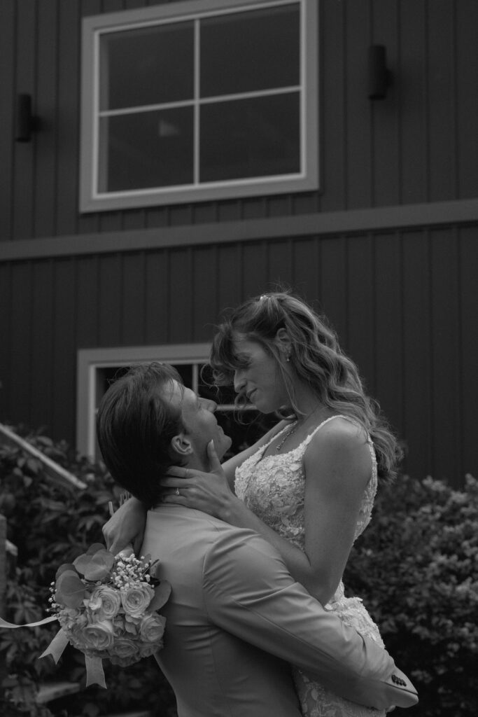 Myles carrying Kayla while she touches his face during their wedding portraits at Hawthorne Estates