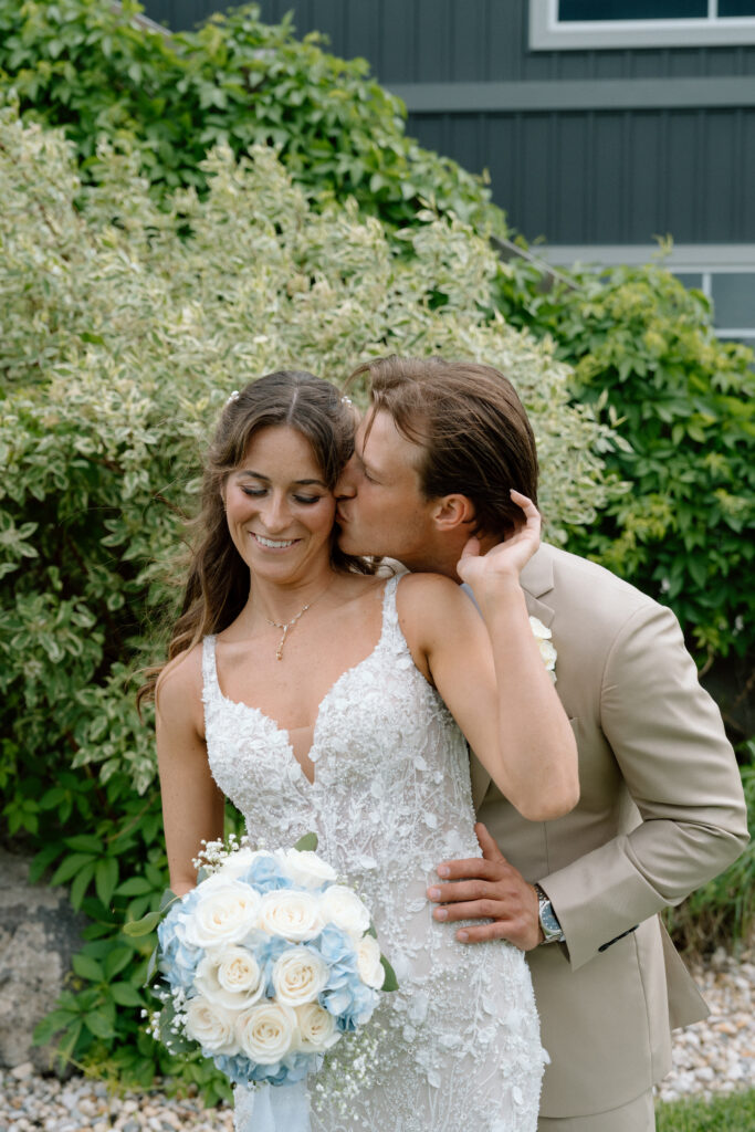 Myles kissing Kayla on the cheek while she smiles shyly during their Hawthorne Estates wedding portraits