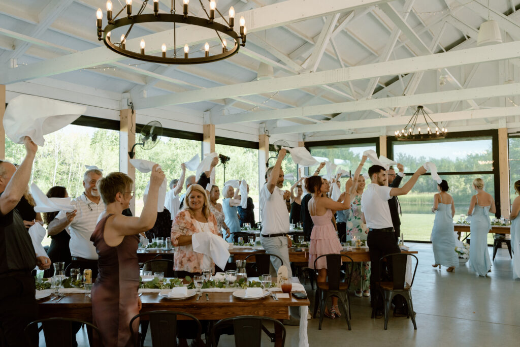Wedding guests waving white handkerchiefs and celebrating during Julianna and Cole's reception at The White Poplar
